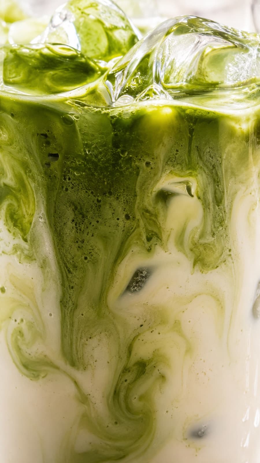 Iced matcha swirling into milk, macro shot