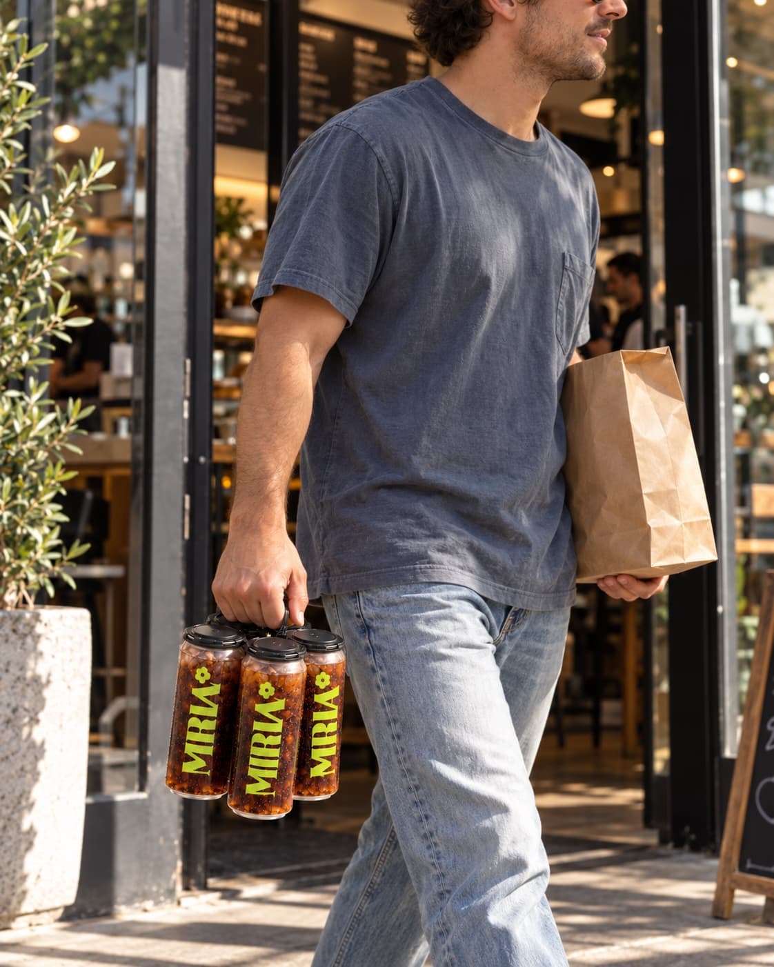 A customer leaving with a takeout bag and a four-pack of sealed cans